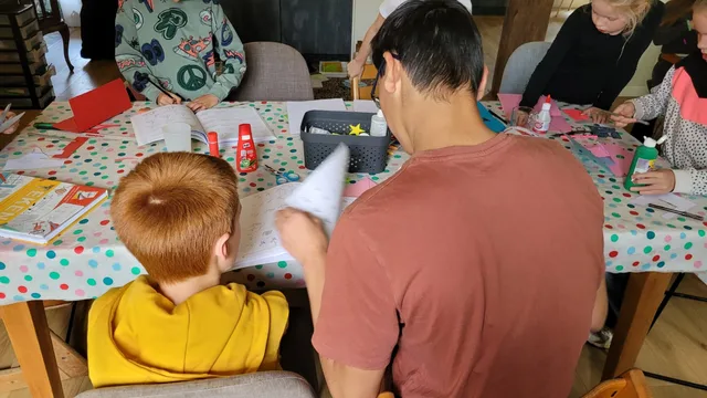 Kinderen en een volwassene knutselen samen bij De Ontmoetfabriek